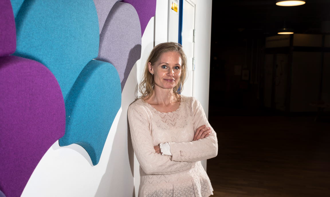 Anna Strandberg står lutad mot en vägg och ler in i kameran.