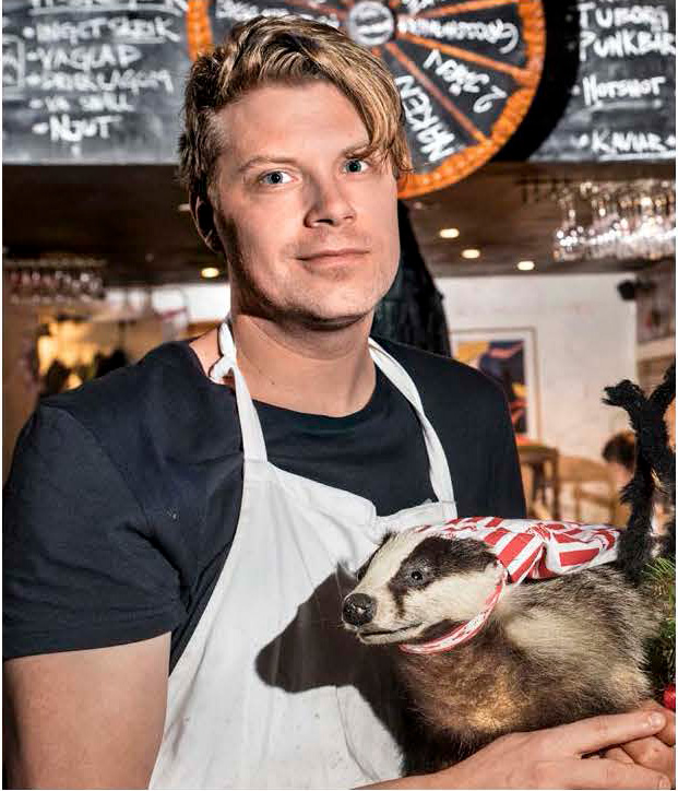 Porträttbild på Joakim Almqvist. Joakim är blond, befinner sig på en restaurang, med en griffeltavla bakom sig. Han håller i ett uppstoppat djur.