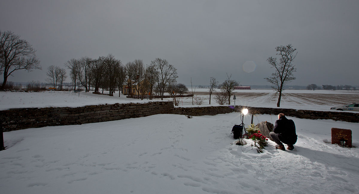 Mats Sjöö sitter på huk vid en gravsten