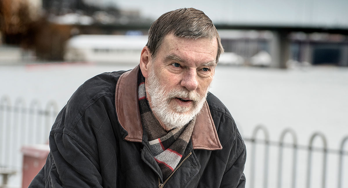 Per Mattson har på sig vinterkläder och sitter utomhus och blickar utåt. Han