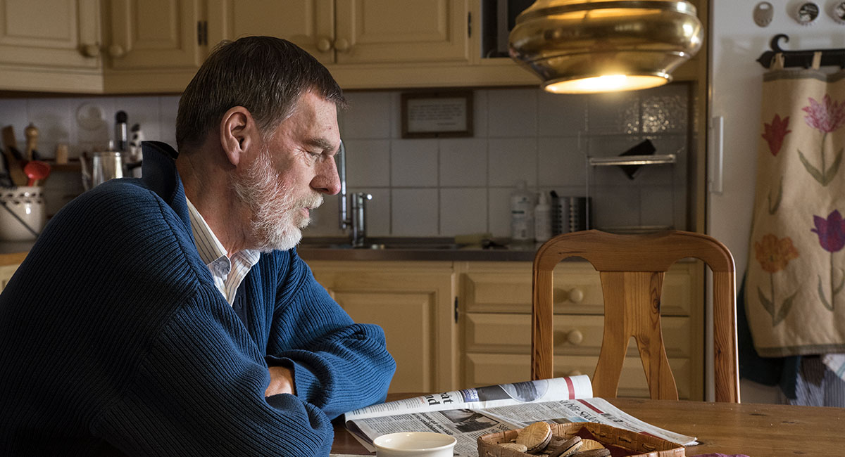 Per Mattson sitter vid ett köksbord och läser en tidning